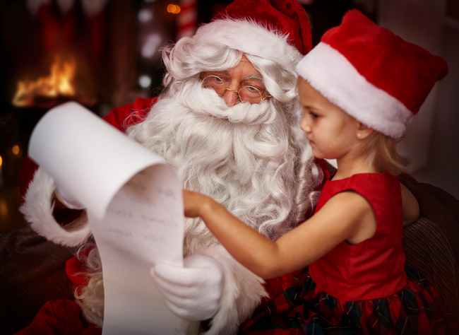 Weihnachtsmann liest gemeinsam mit kleinem Mädchen eine Wunschliste – professionellen Weihnachtsmann buchen für festliche Auftritte
