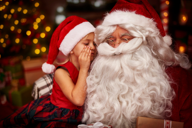 Kind flüstert dem Weihnachtsmann ihren Wunsch ins Ohr – Weihnachtsmann buchen für Familienfeiern und Events